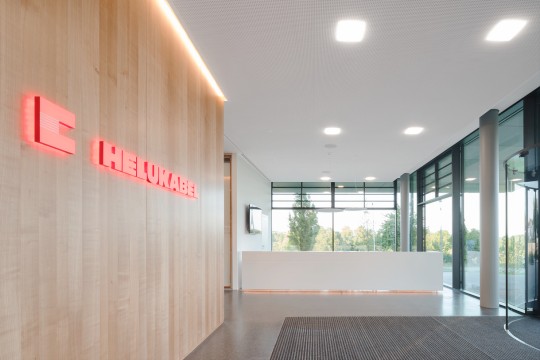 The HELU headquarters' entrance is shown empty and well-lit in the daylight.