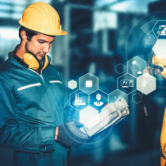 engineer looking at an automated robot within a factory.