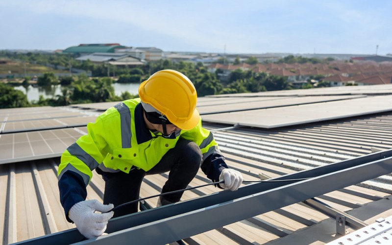 Man working on a photovoltaic system on the roof of a house
