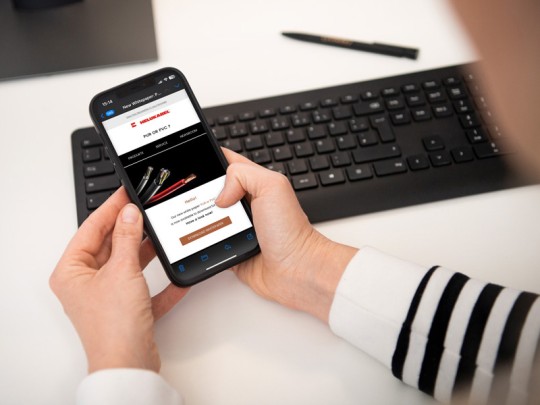 Person liest HELU Newsletter am Smartphone