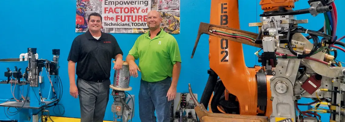 Zwei Personen neben einem Roboterarm