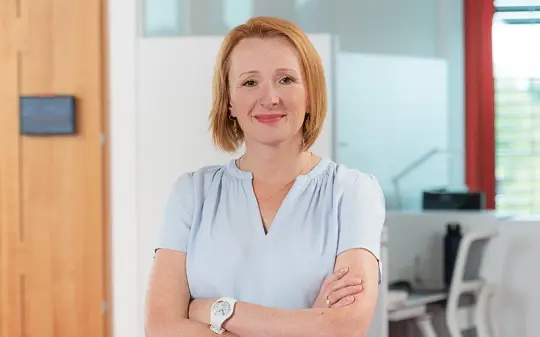 Katja stands in the office at HELUKABEL with her arms crossed.